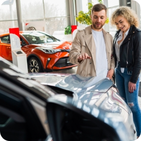 Couple looks at new vehicles at a car dealership.  